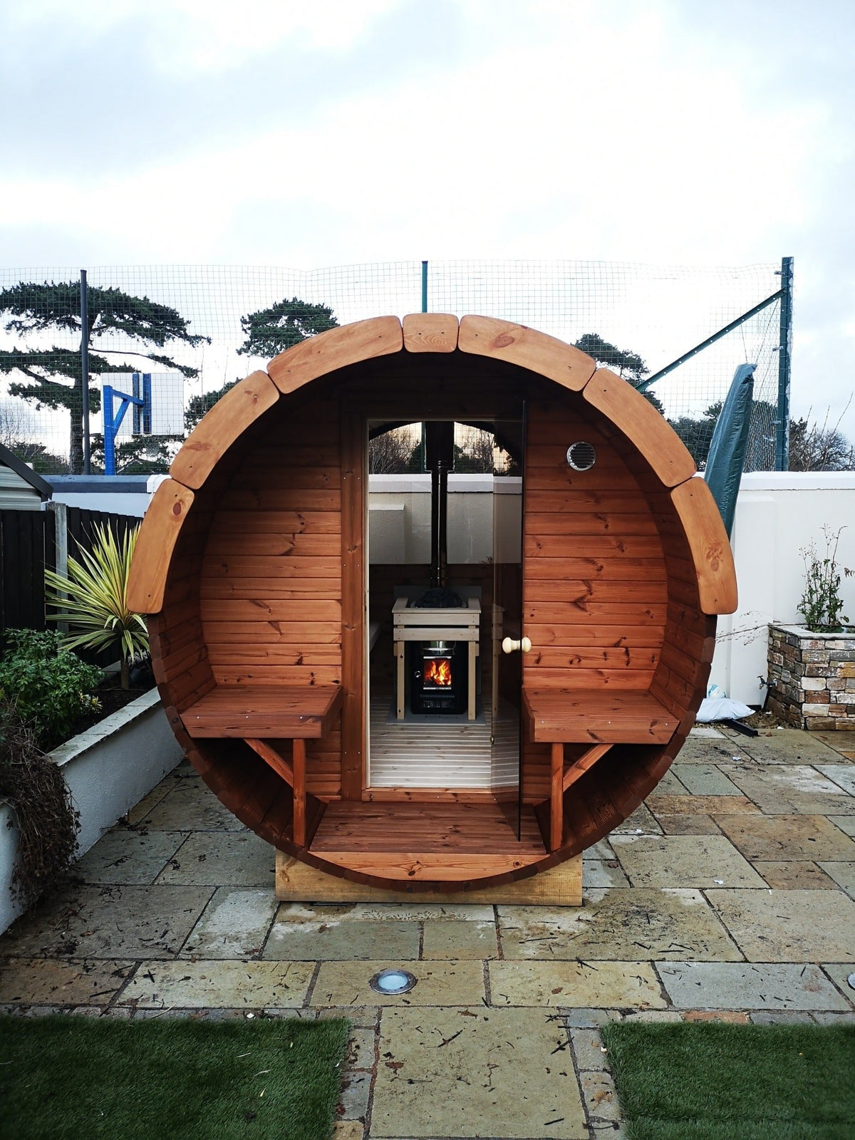 Holvi 240 barrel sauna on a patio, terrace benches either side of the door