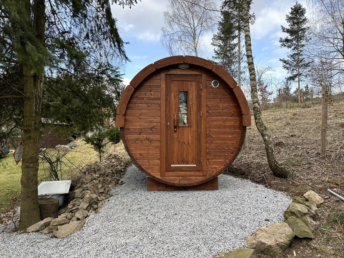Holvi 350 thermowood barrel sauna on a gravel base in a woodland garden