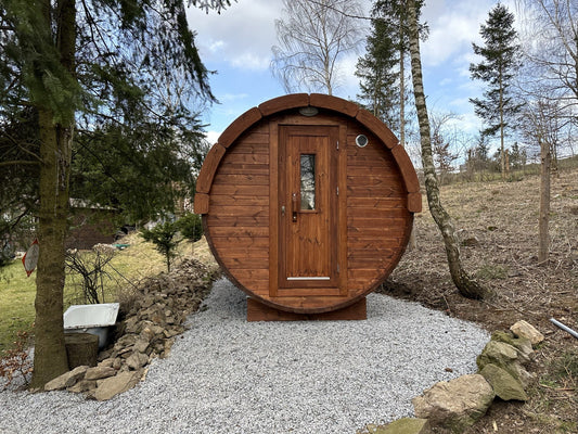 Holvi 350 thermowood barrel sauna on a gravel base in a woodland garden