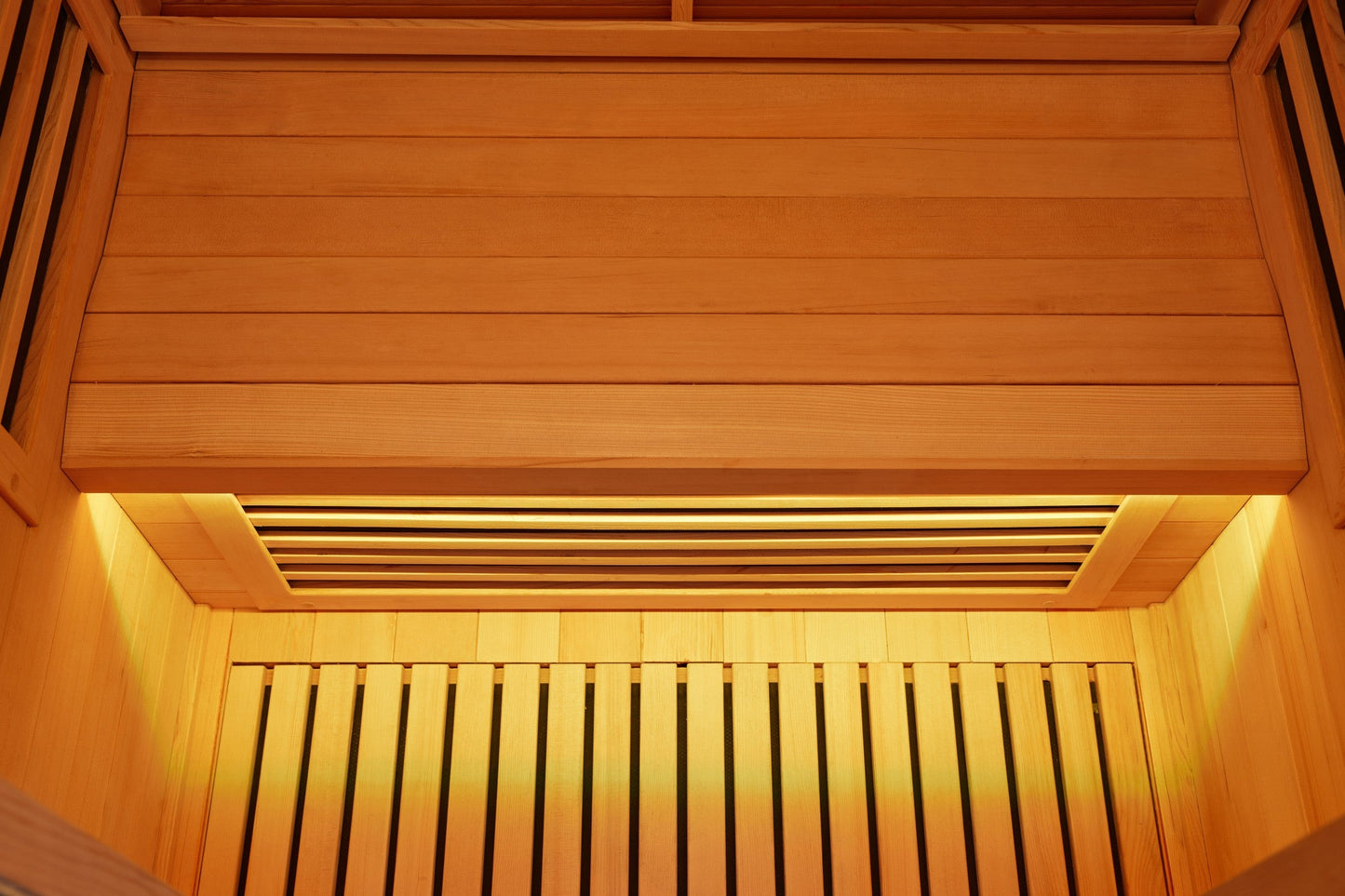 Cedar-lined sauna interior looking up at the ceiling and upper bench, lit by a warm LED strip along the edge