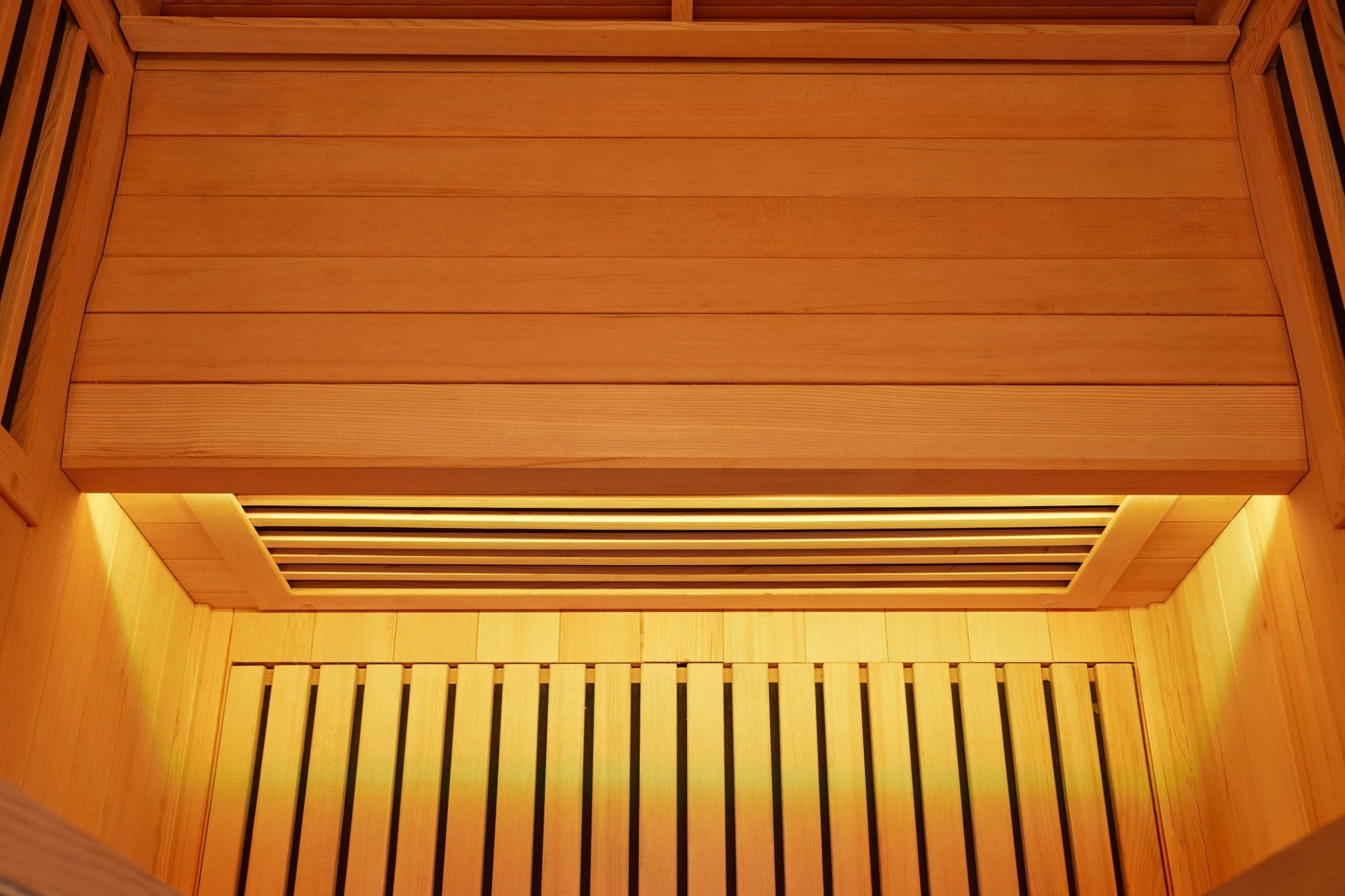 Cedar-lined sauna interior looking up at the ceiling and upper bench, lit by a warm LED strip along the edge