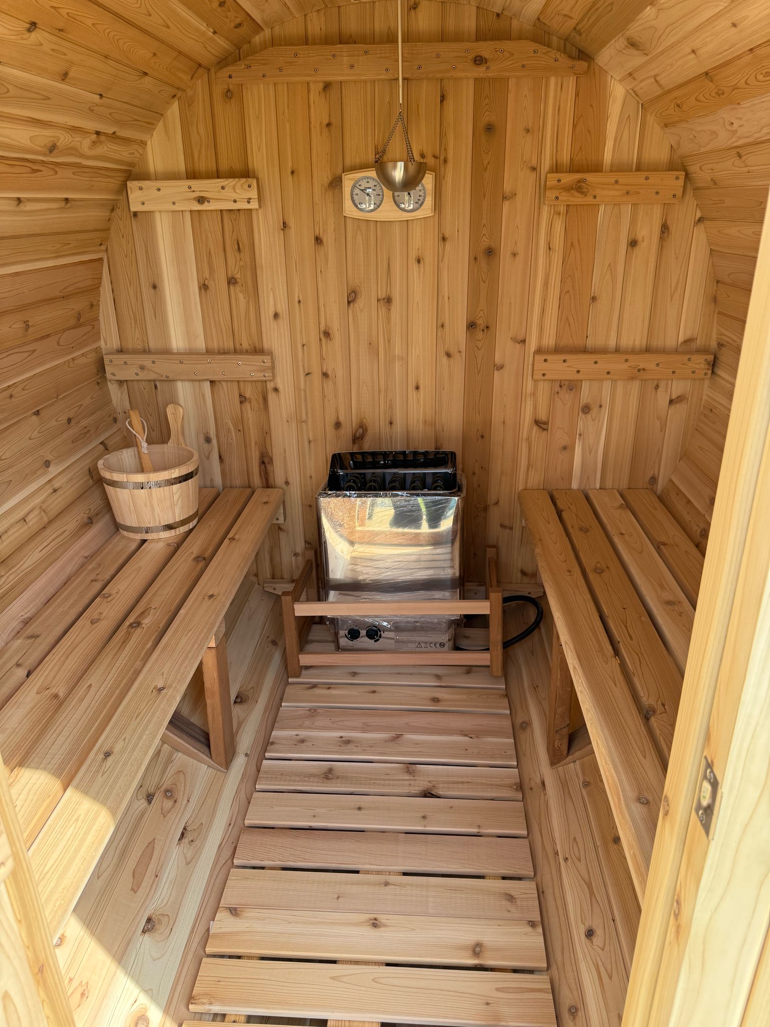 Four person barrel sauna installed on a garden patio