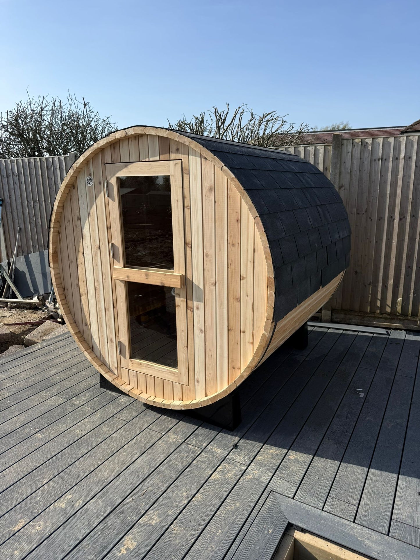 Barrel sauna standing on its timber cradles in a garden setting