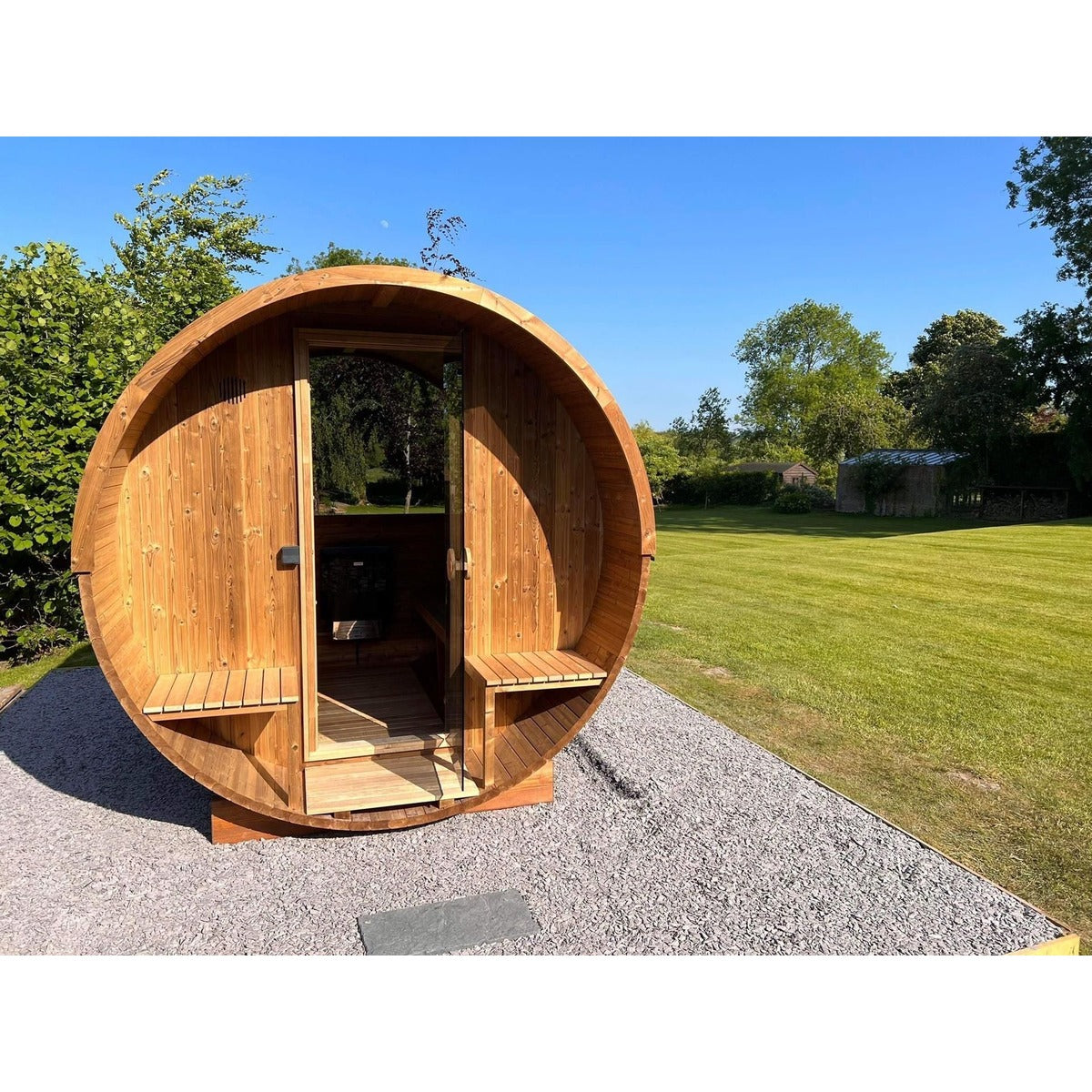 Hekla Barrel Sauna 250 outdoor sauna cabin, front view on grass (lifestyle image).