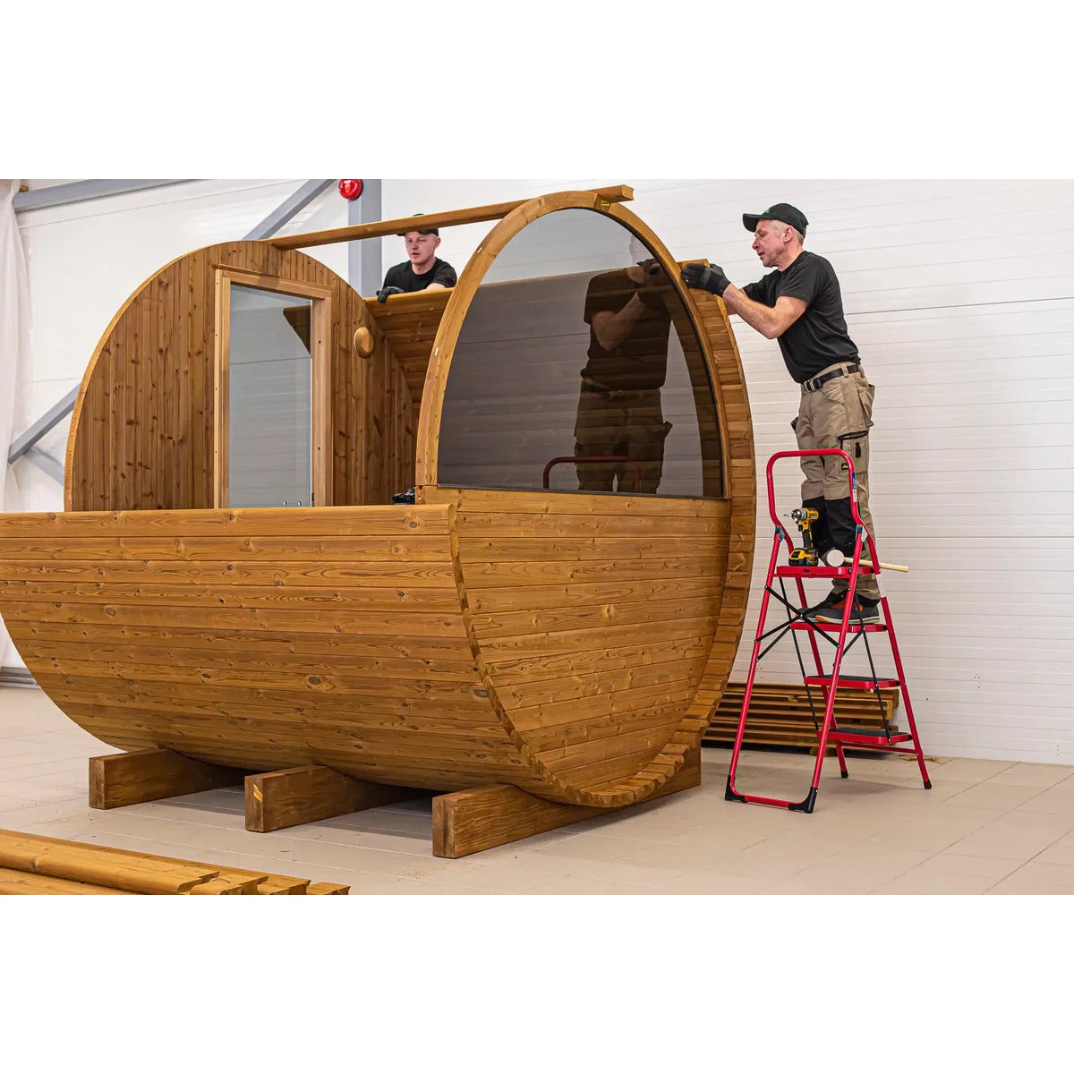Factory assembly image showing barrel sauna frame installation.