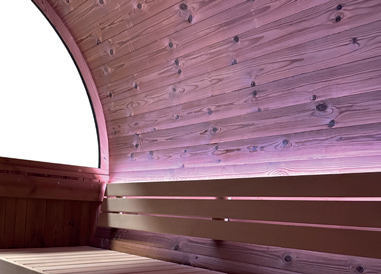 Holl's Onyxia Barrel black ThermoWood barrel sauna with chimney on a stone patio