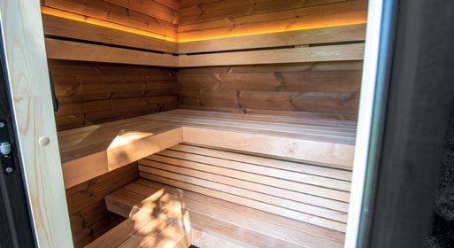 Holl's Onyxia Cube outdoor sauna with mirrored glass facade reflecting sky in a field