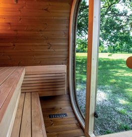 Holl's Onyxia Cube outdoor sauna with mirrored glass facade reflecting sky in a field