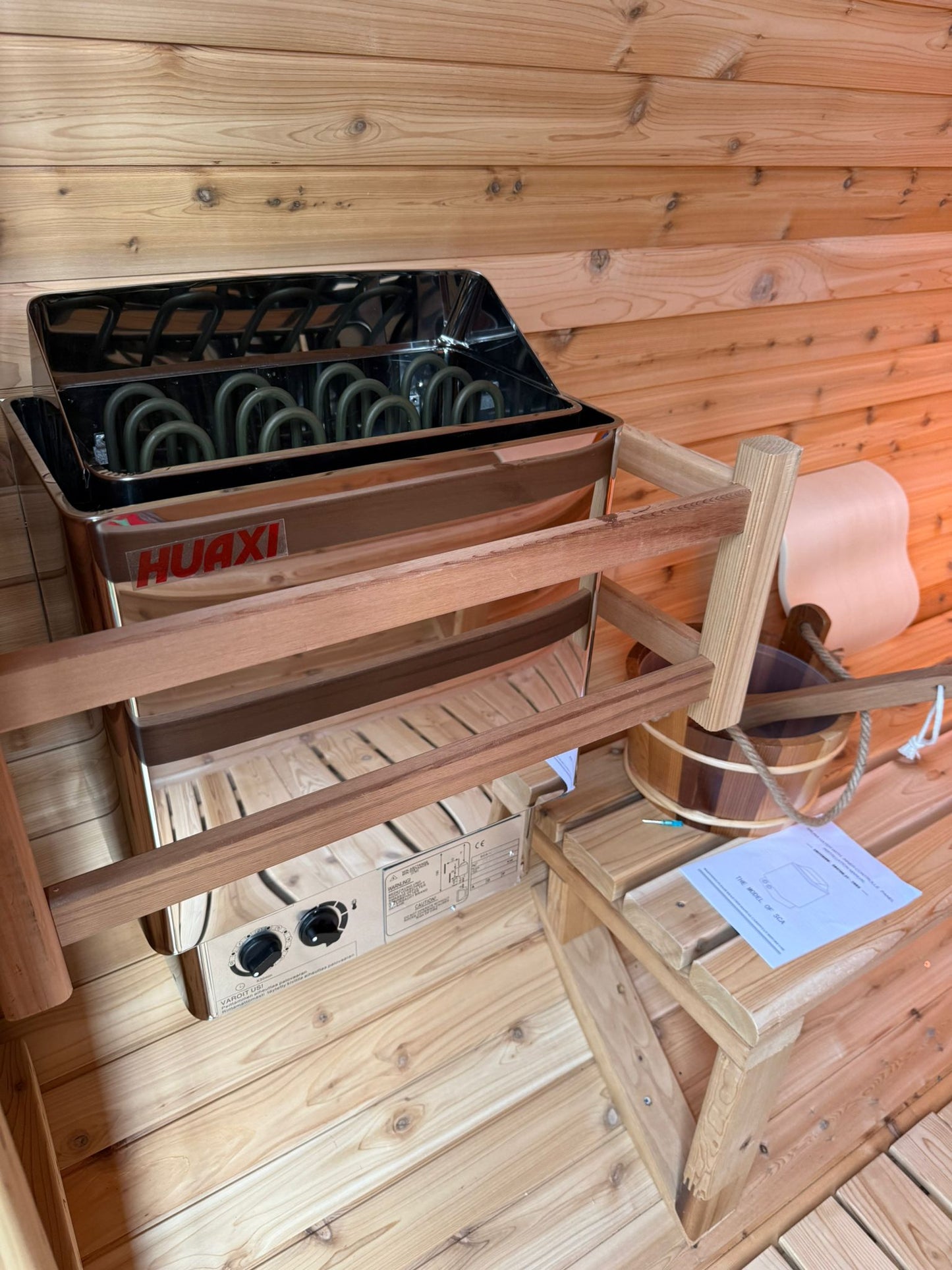 Panoramic barrel sauna set up in a garden with open fields behind